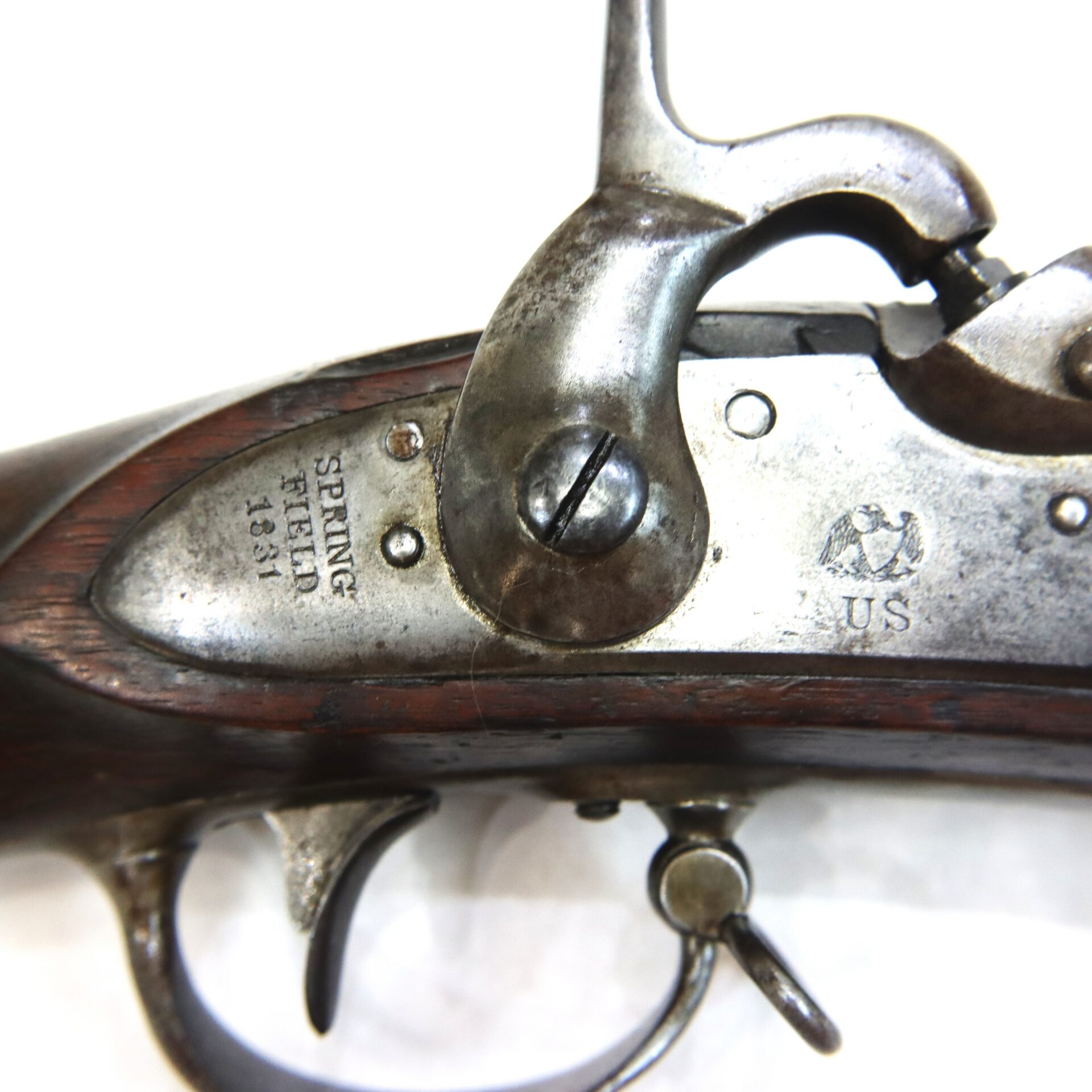 Close-up of an antique firearm lock mechanism, with engraved markings “Springfield 1851” and “U.S.” visible on the metal plate.
