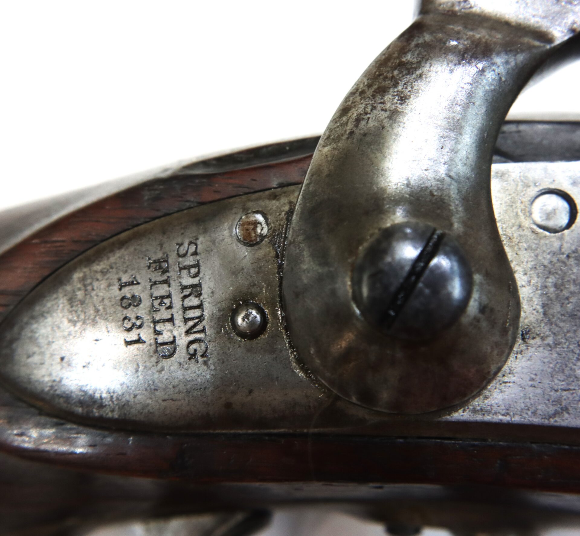 Close-up of a metal and wood firearm mechanism stamped with “SPRINGFIELD 1831” on the metal surface.
