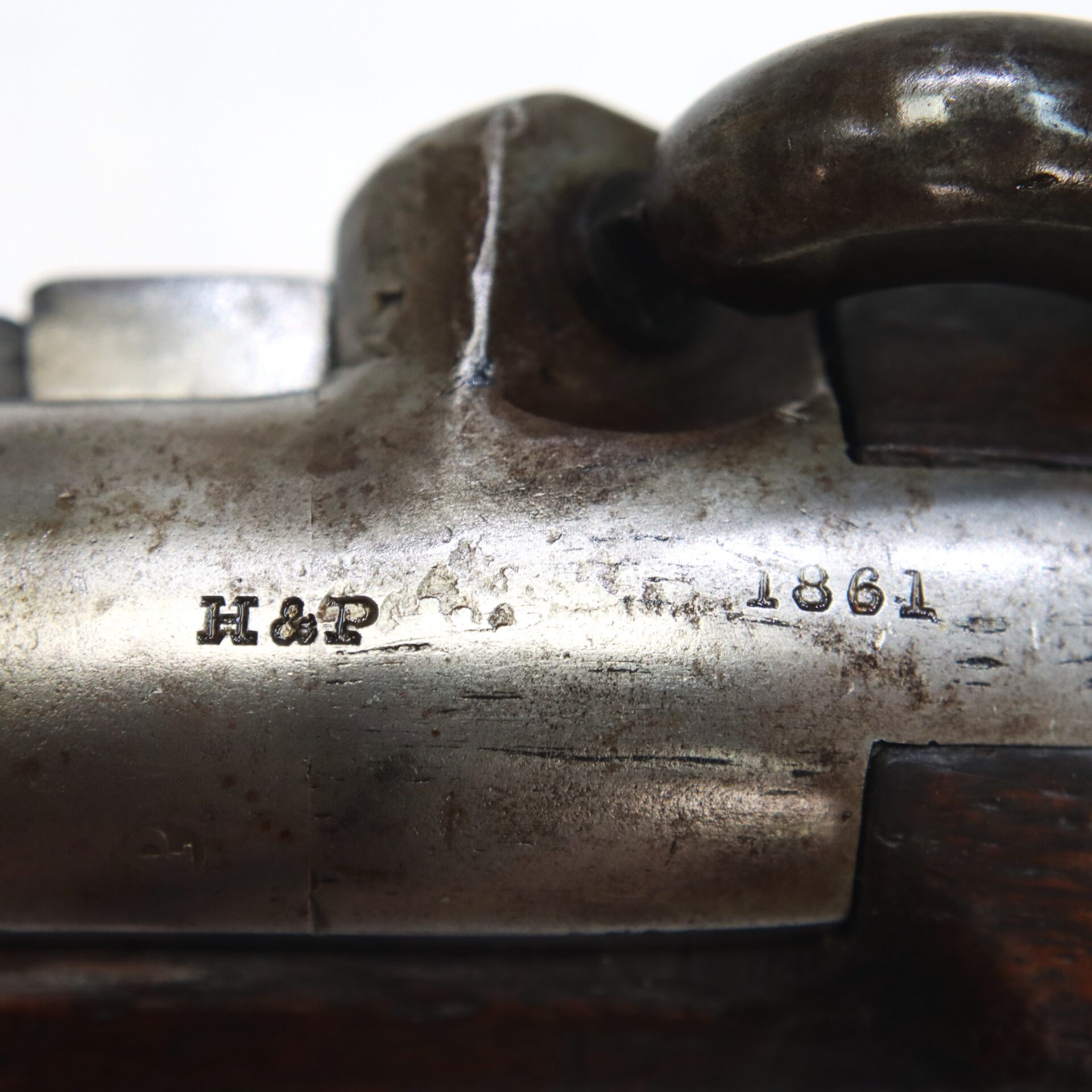 Close-up of a metal rifle part stamped with “H&P” and “1861,” showing worn and aged surface with visible engravings.