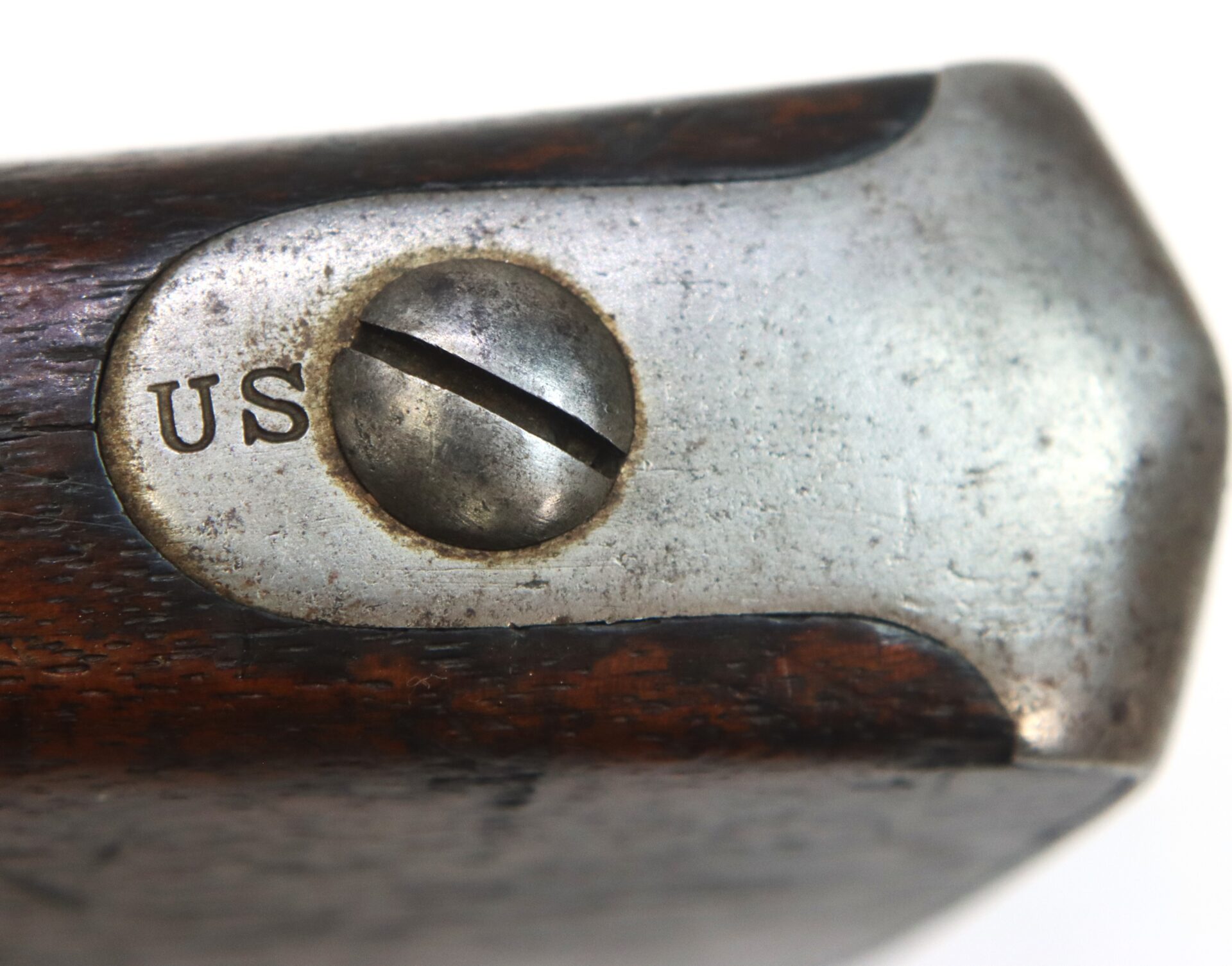 Close-up of a metal screw head on a wooden surface, with “US” engraved next to the screw.