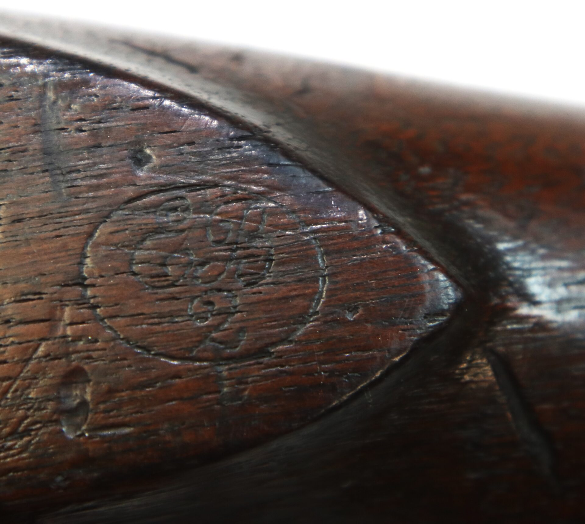 Close-up of a wooden rifle stock showing a circular stamp with the numbers “52” and other worn markings.