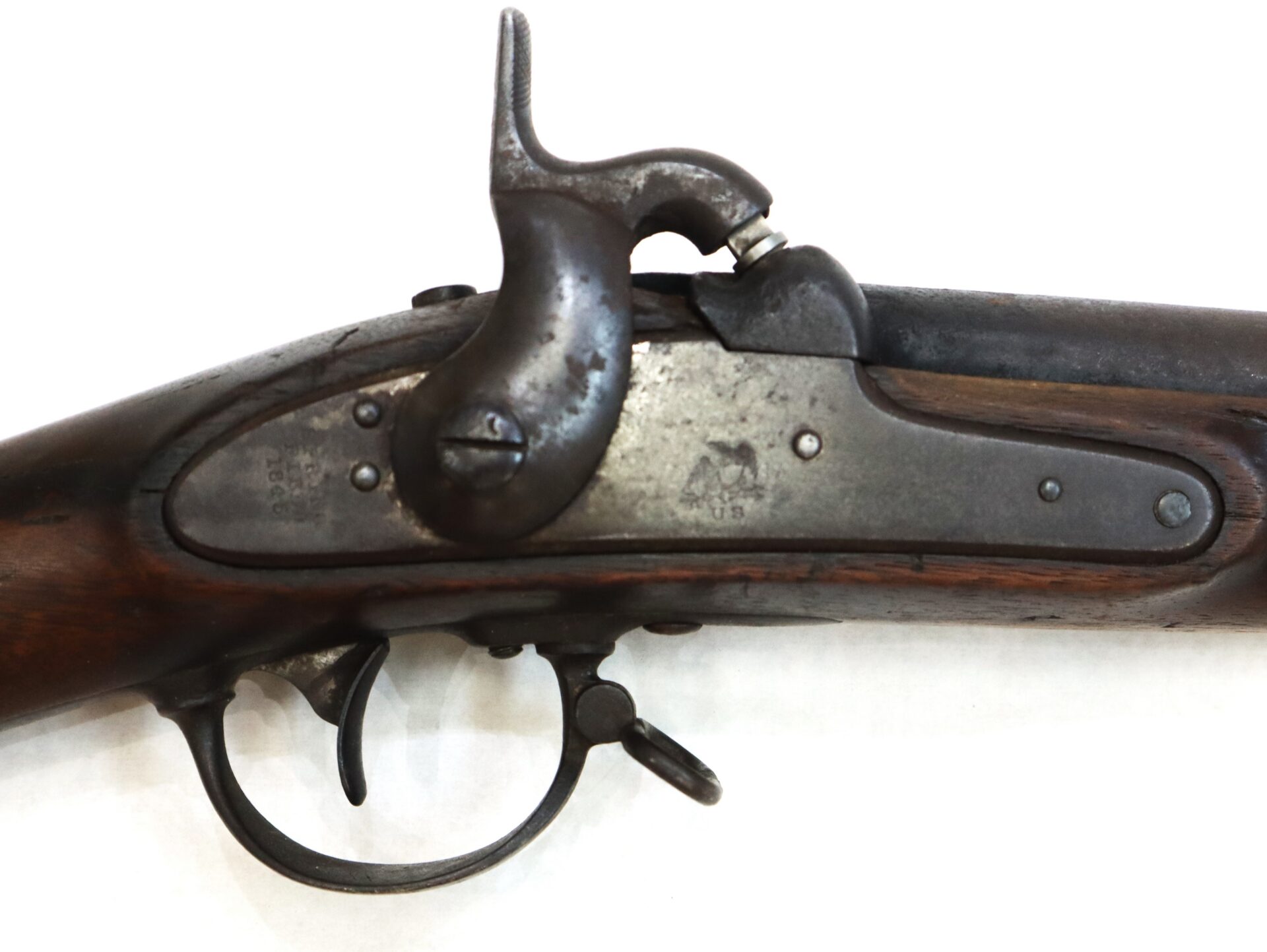Side view of an antique percussion cap musket lock mechanism with a wooden stock and metal trigger, photographed against a white background.
