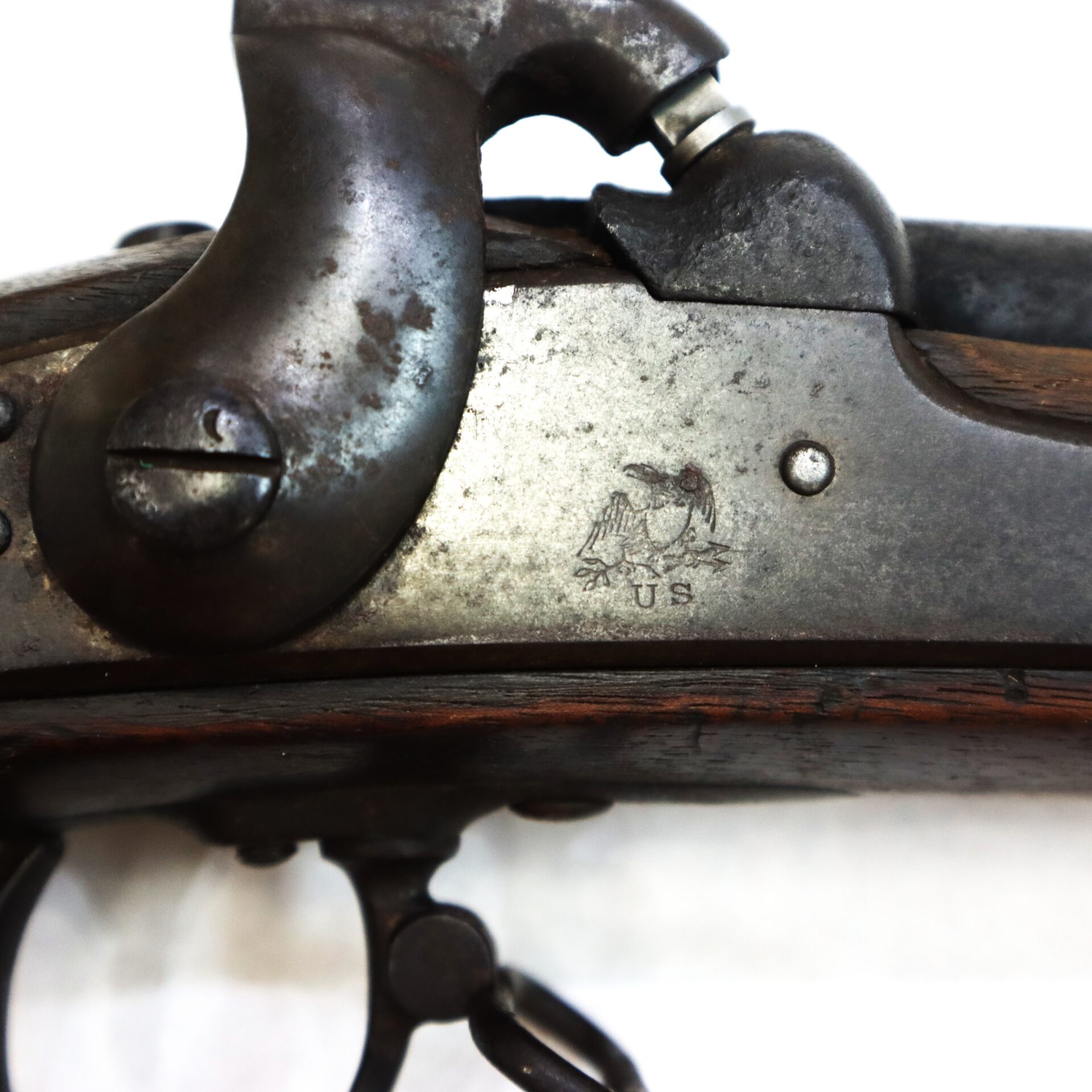 Close-up of the metal lock plate on a Model 1842 .69 Caliber Springfield Smoothbore Musket, showing an eagle engraving above the letters “US.”