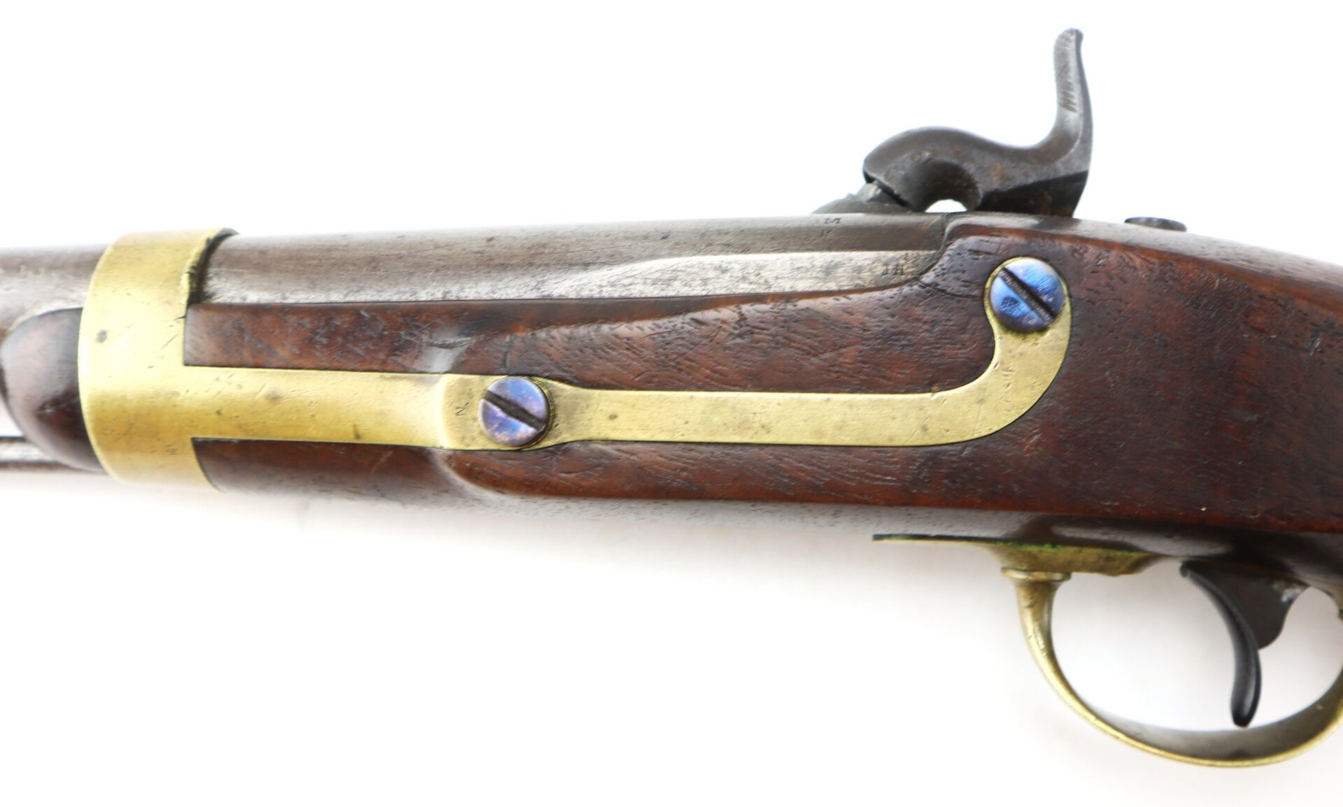 Close-up of an antique flintlock or percussion pistol, showing the wooden grip, brass fittings, blue screws, and trigger mechanism.
