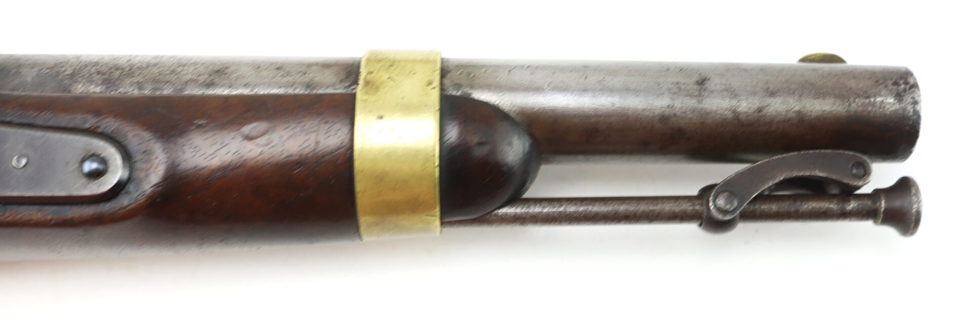 Close-up of the barrel and wooden stock of an antique firearm with a brass band and metal ramrod visible.
