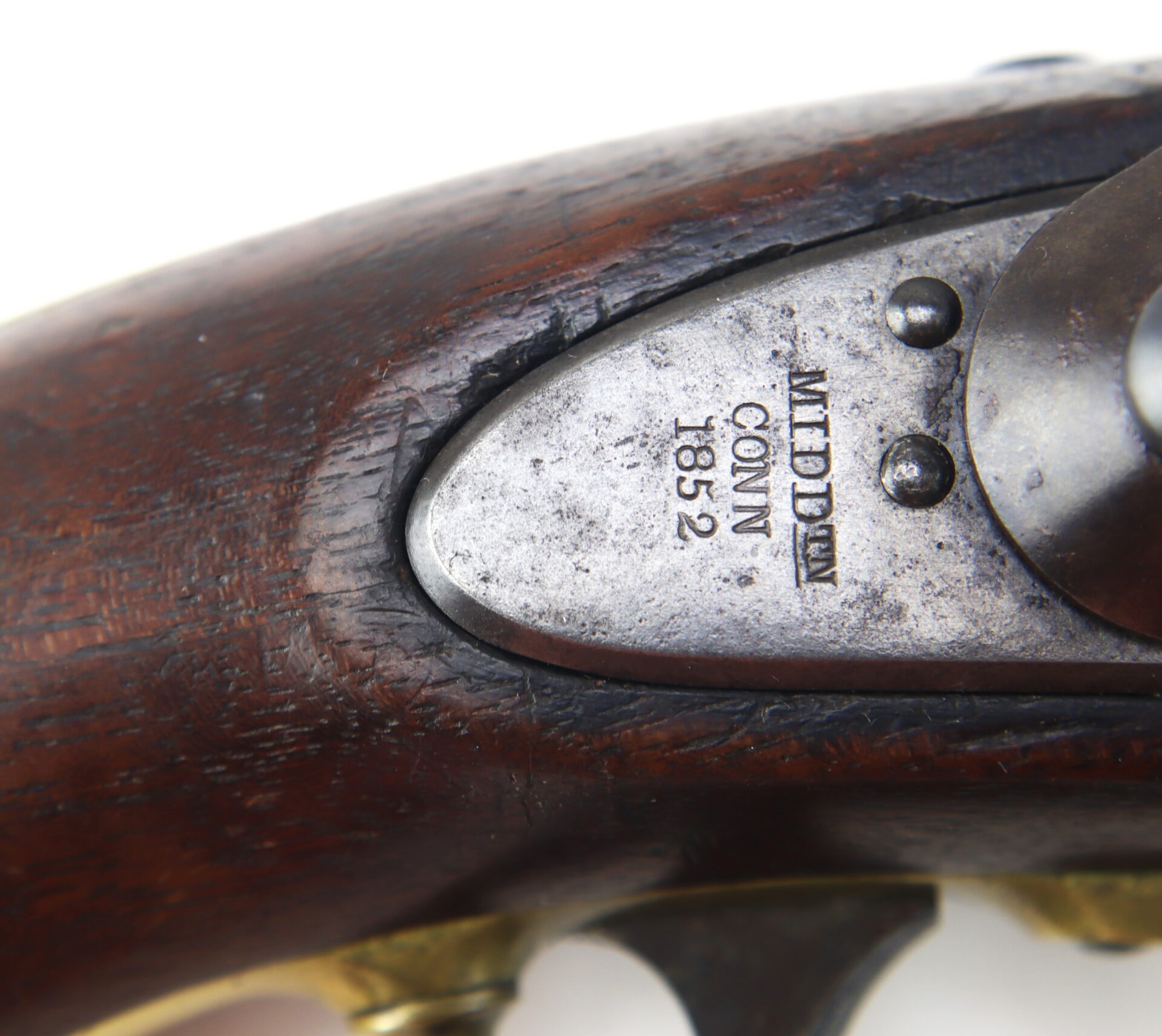 Close-up of a metal plate on a wooden firearm stamped with “MIDDLETOWN CONN 1852.” The metal appears worn and aged, with visible screws and part of the trigger mechanism.