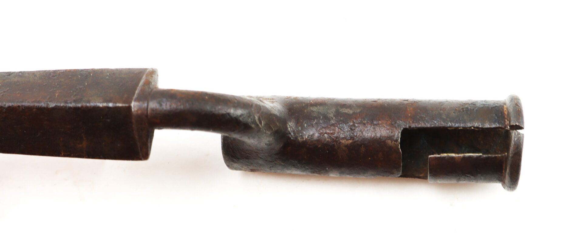 Close-up of a rusty, antique metal tool with a cylindrical, slotted end and a slightly bent shaft, shown against a white background.