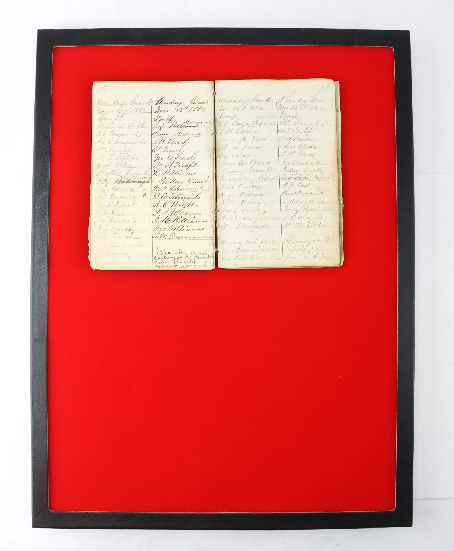 An old handwritten ledger or register is displayed open in a black frame with a bright red background.