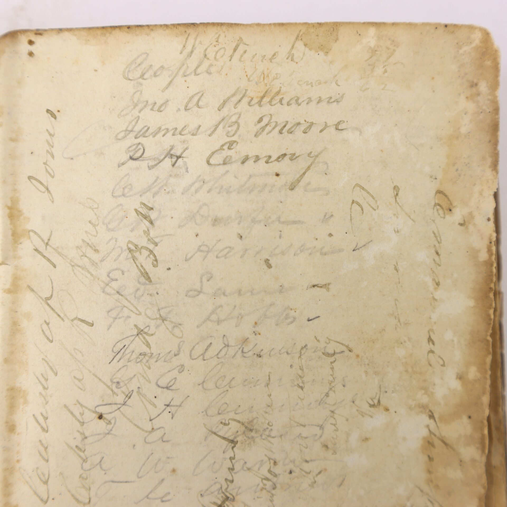 Aged paper page with multiple handwritten names in cursive, some faded; edges are worn and stained, writing overlaps in several places.