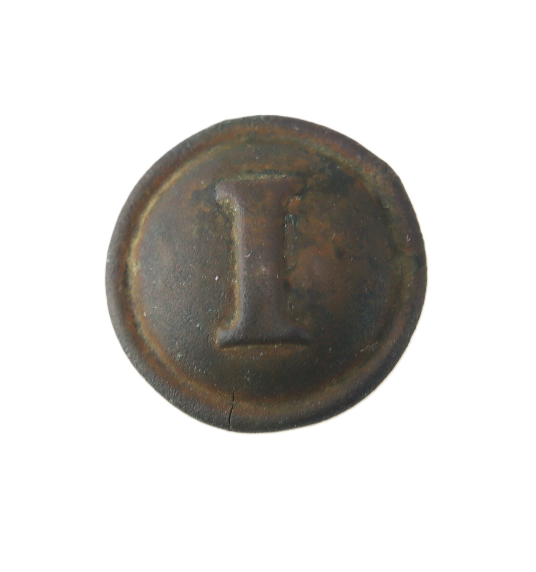 A round, weathered metal button with a raised letter “I” in the center, photographed against a white background.