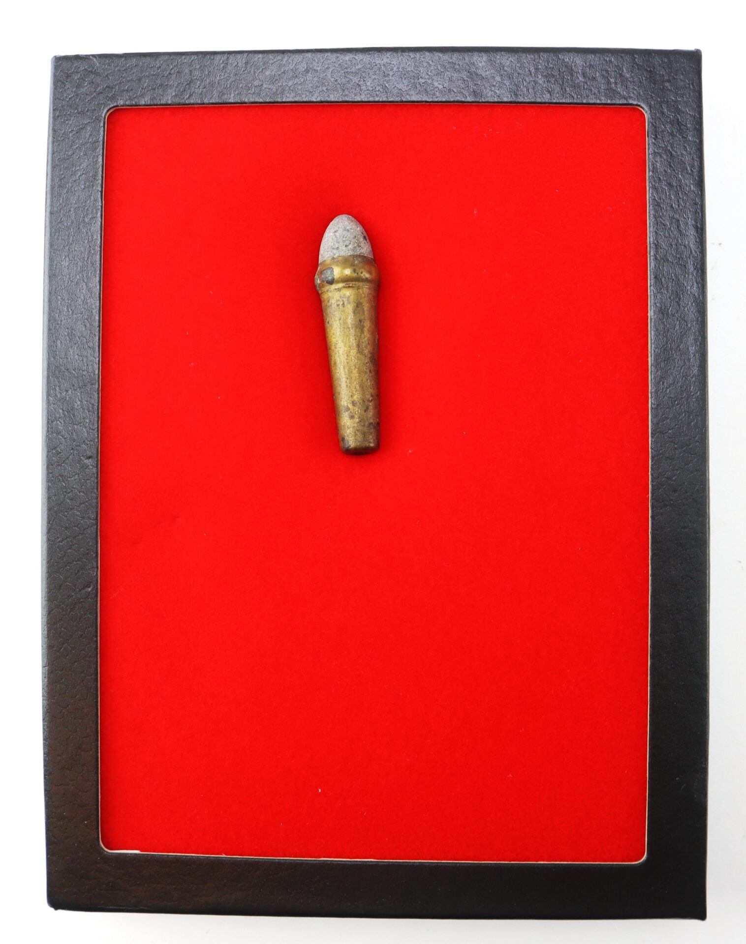 A single old bullet with a gray tip is displayed upright in the center of a red background within a black square frame.