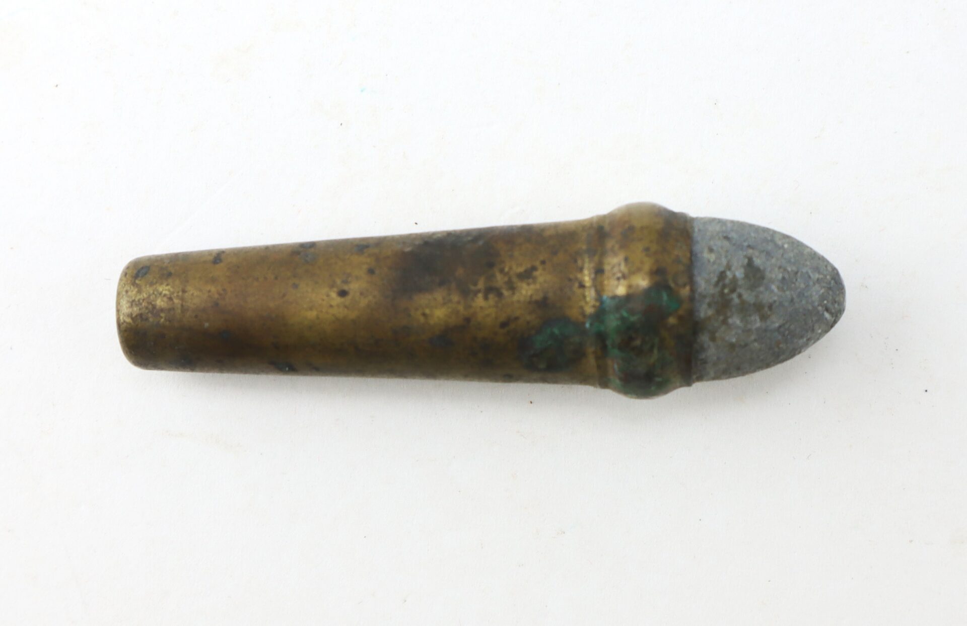 A corroded, vintage bullet with a brass casing and a grayish metal tip is shown on a plain white background.