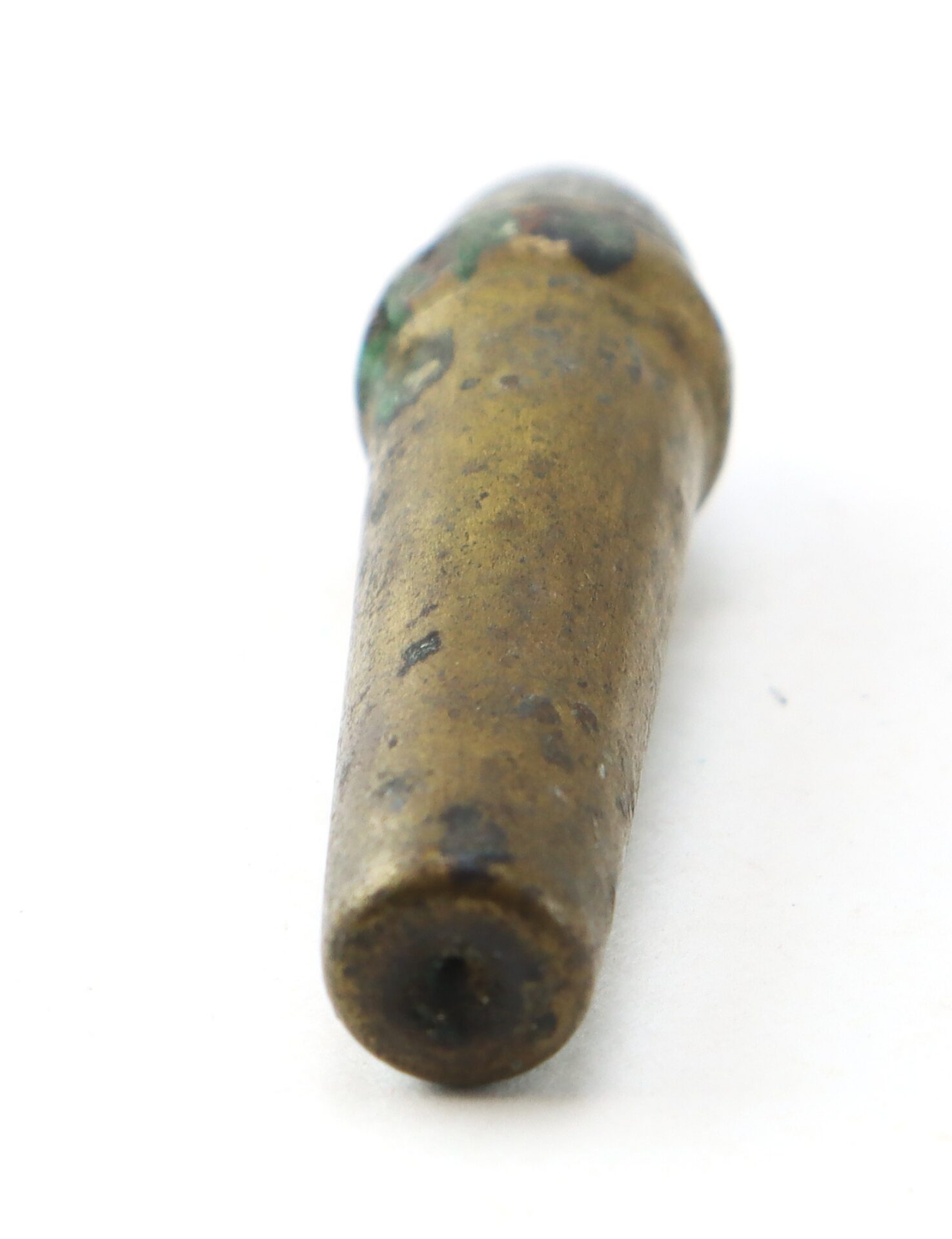 A tarnished, cylindrical brass object with a rounded top and a small hole at its flat end, shown against a white background.