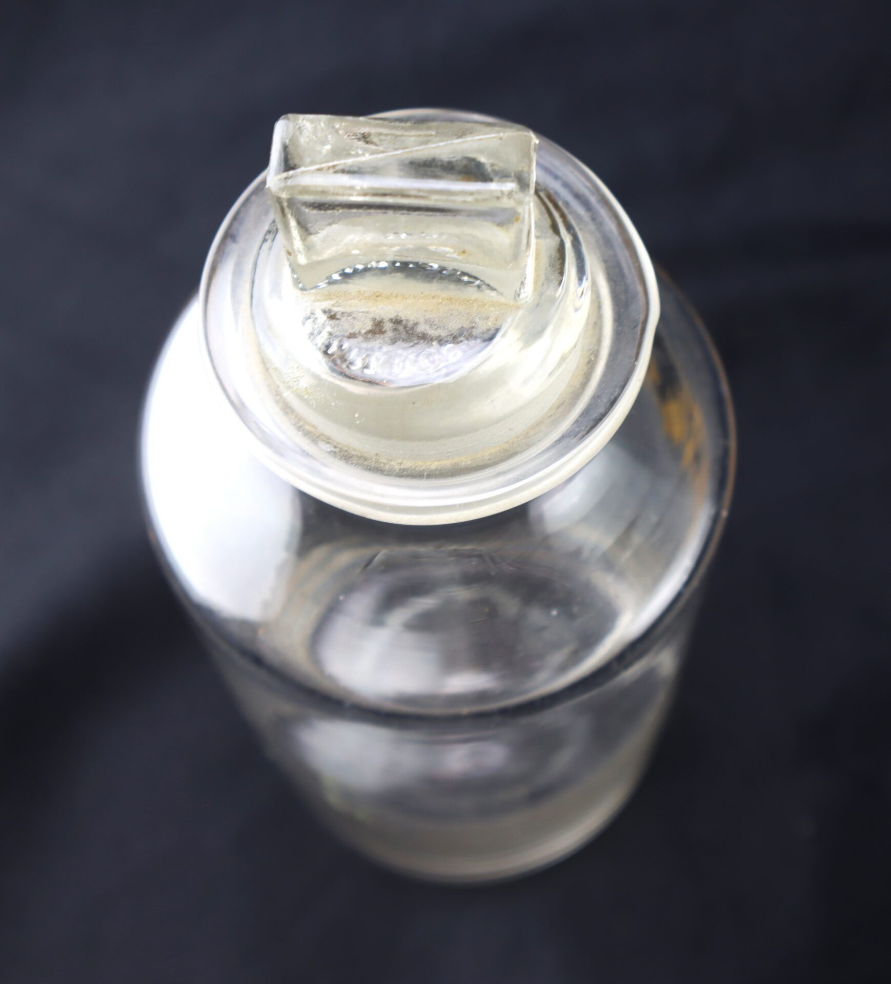 Clear glass jar with a matching glass lid, viewed from above, set against a dark background.