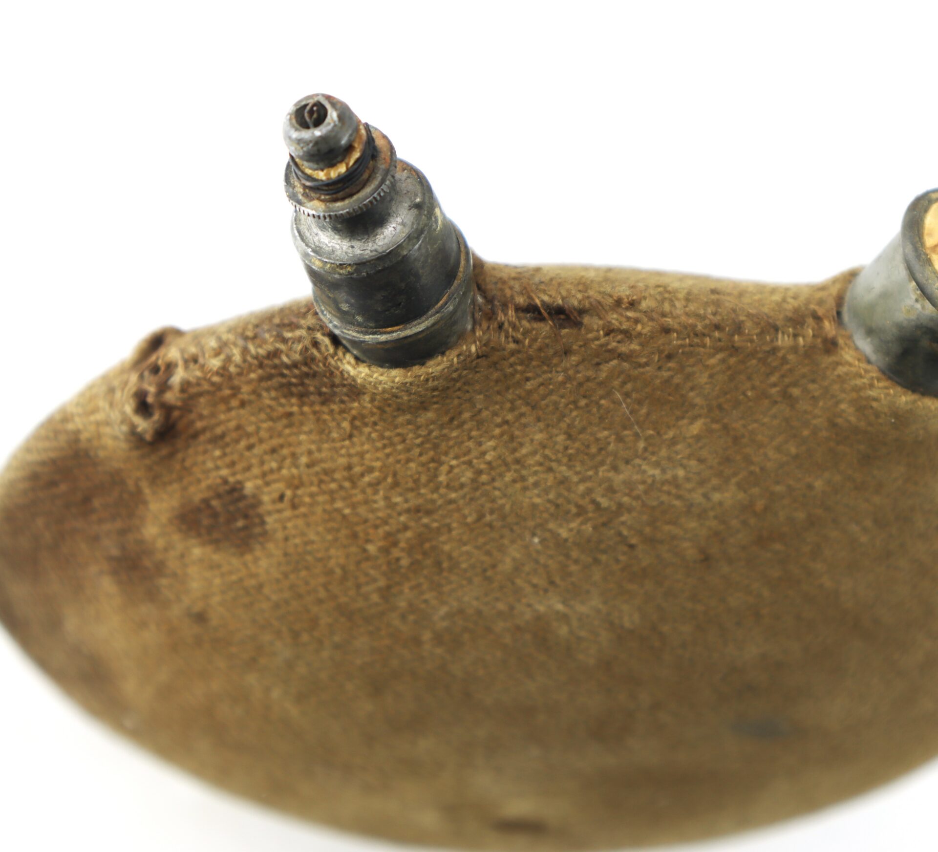 Close-up of a worn, brown, vintage American football with a visible inflation valve and stitching against a white background.