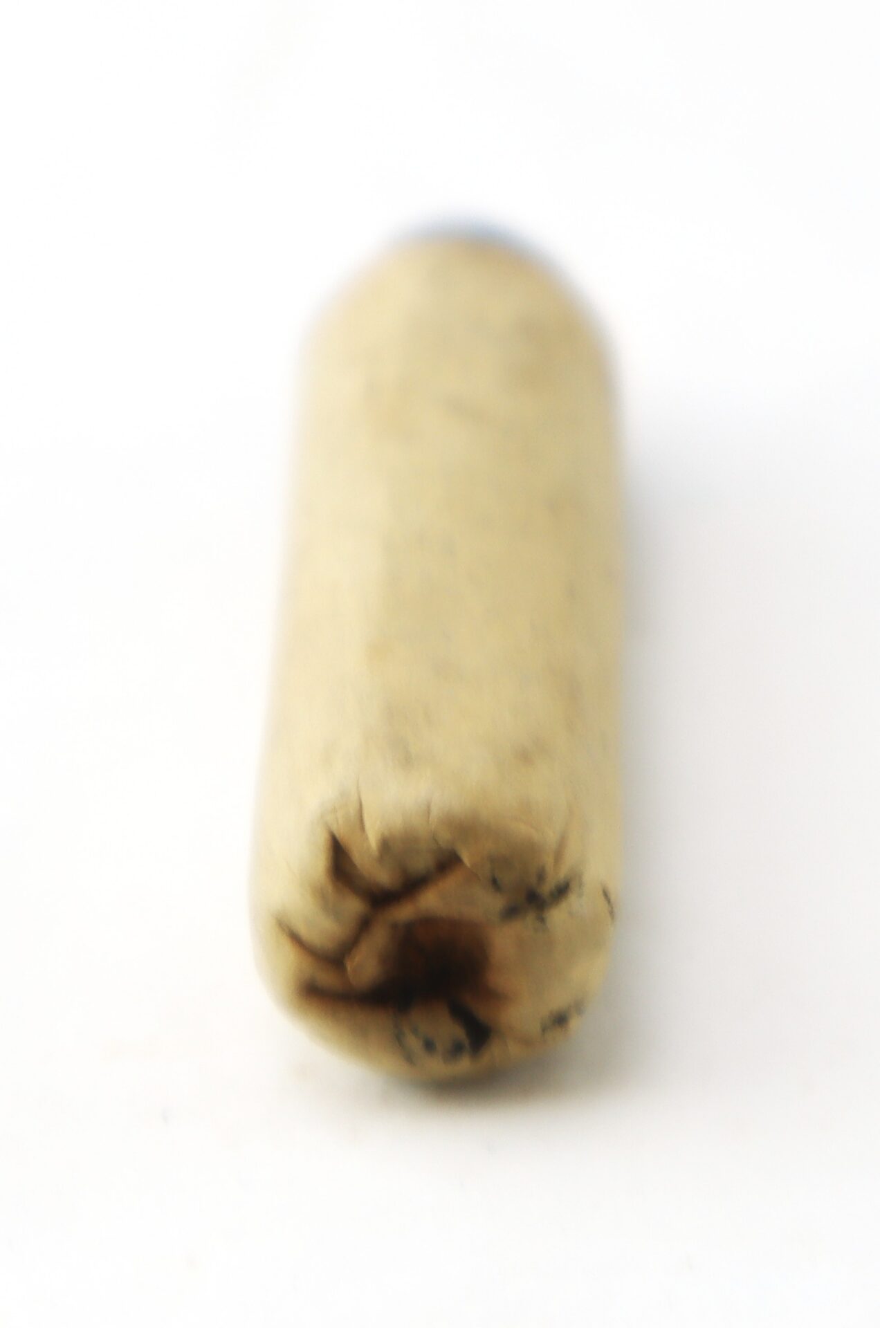 A close-up of a single, unlit hand-rolled cigarette or joint on a white background, with a focus on the sealed end.