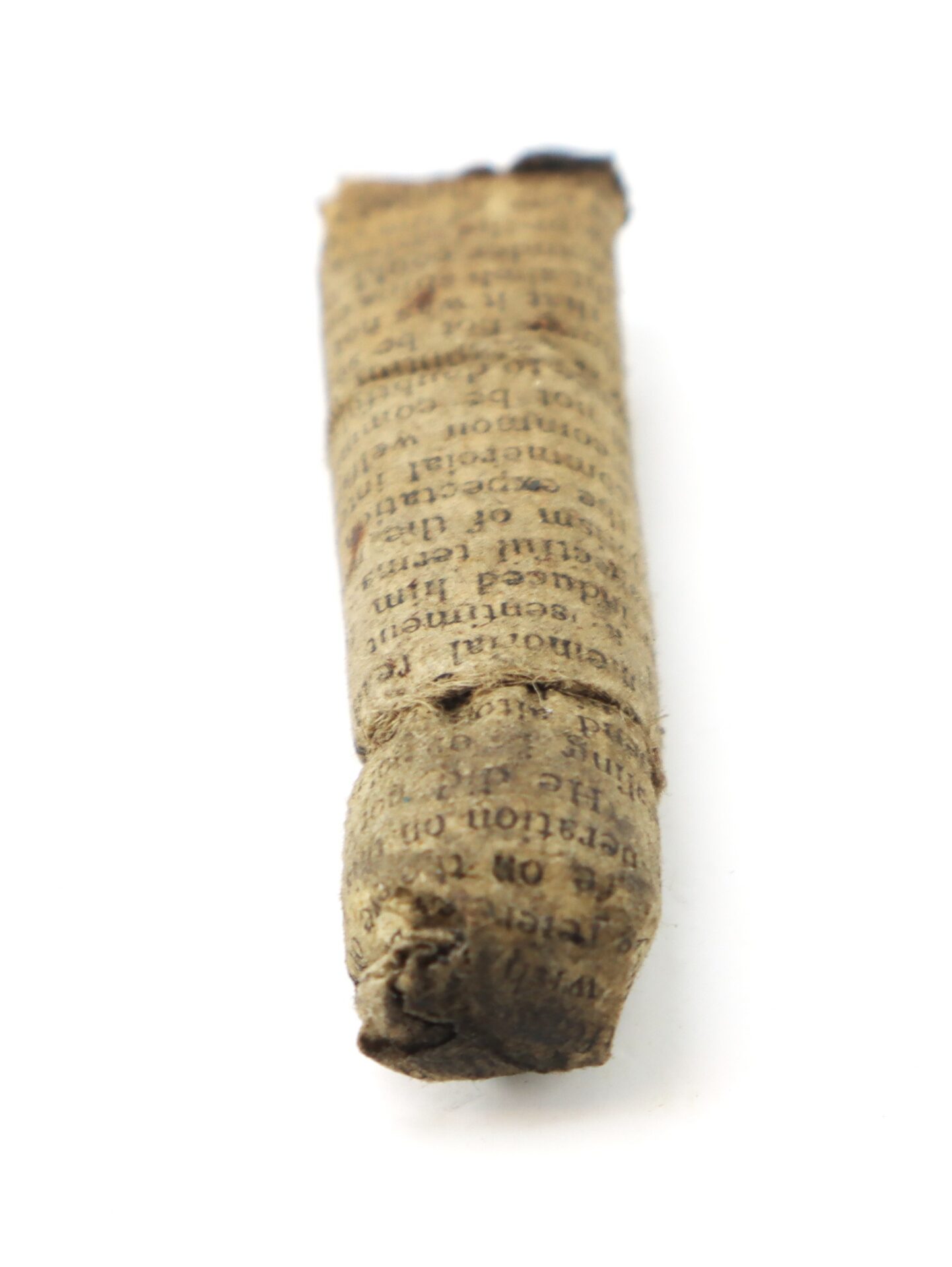 A small cylindrical object wrapped in old printed paper, lying on a white background.