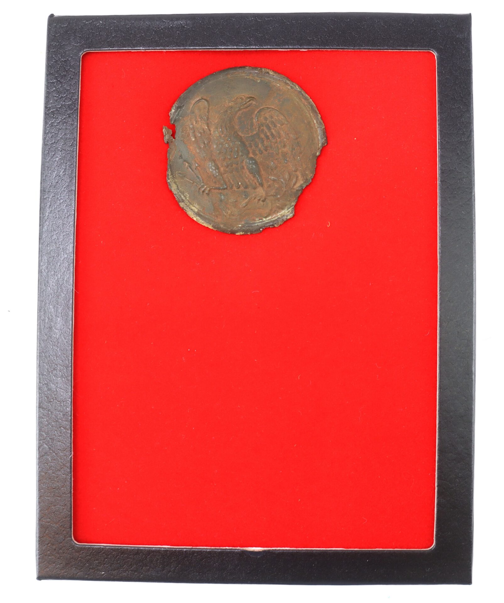 Round, weathered coin or medallion with an eagle design, displayed on a bright red background inside a black rectangular frame.