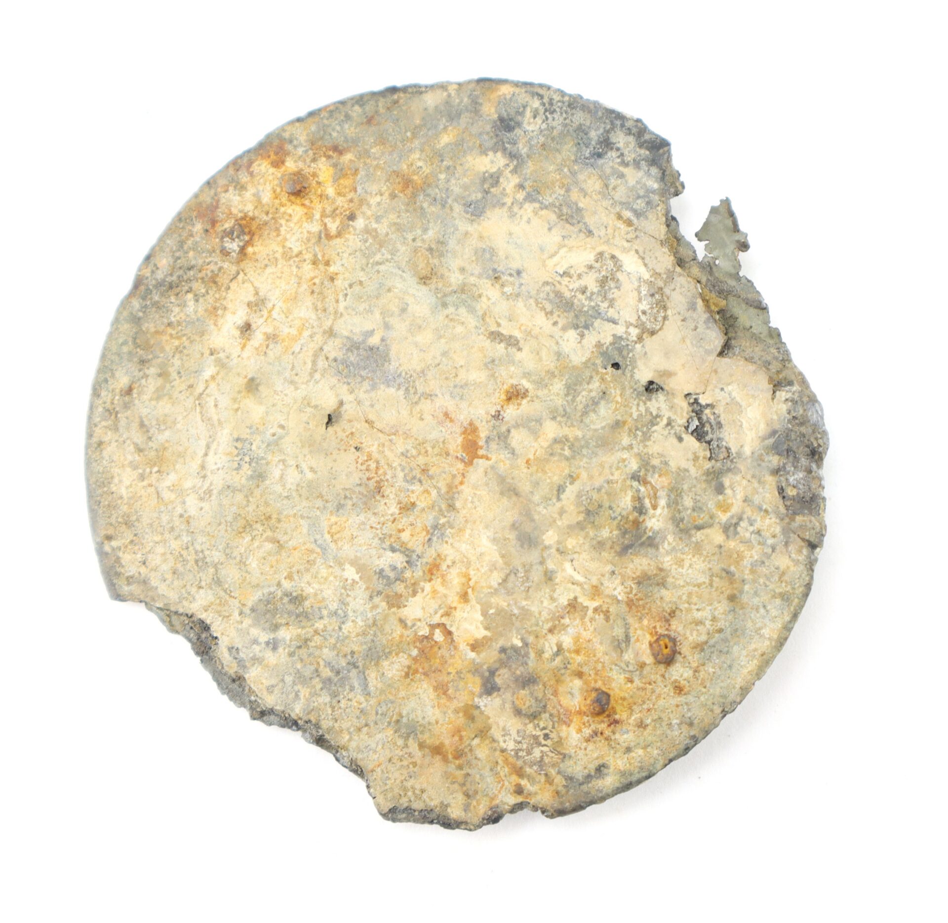 A corroded, circular metal object with a rough, uneven surface and a broken edge, displayed against a white background.