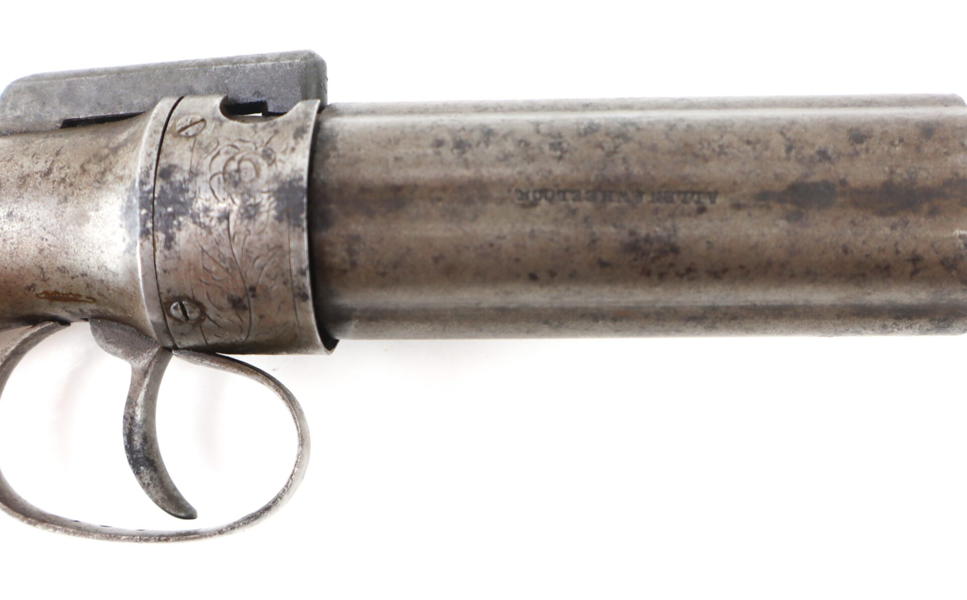 Close-up of an antique, metal double-barreled firearm showing the trigger, trigger guard, and part of the engraved barrel.