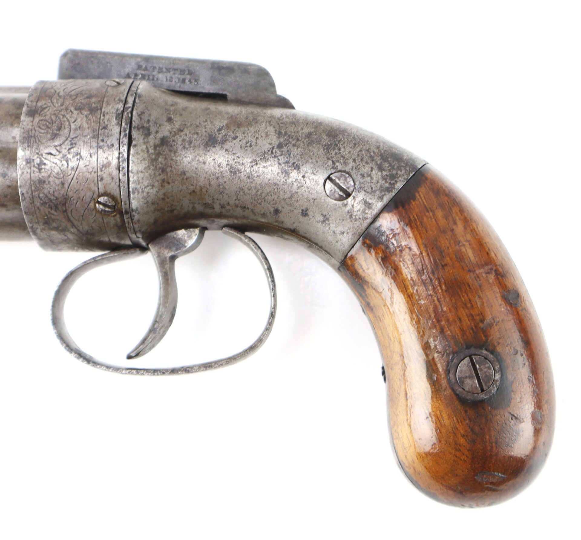 Close-up view of an antique revolver’s trigger and wooden grip, showing metal wear and engraved detailing.