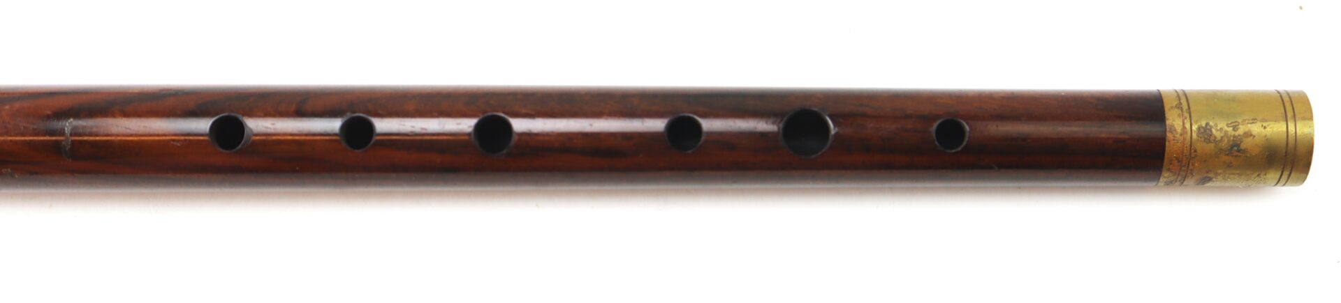 A wooden flute with six finger holes and a brass band at one end, displayed on a white background.