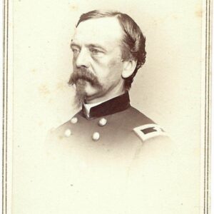 Black and white portrait of a man in a military uniform with shoulder straps and buttons, facing left, with a mustache and sideburns. Handwritten text is visible at the bottom of the image.