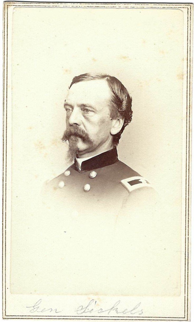 Black and white portrait of a man in a military uniform with shoulder straps and buttons, facing left, with a mustache and sideburns. Handwritten text is visible at the bottom of the image.