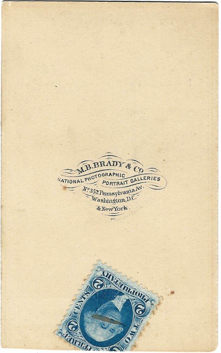 Back of a vintage carte de visite (CDV) titled “CDV of the Grizzly Bear Chair is a Gift from Hunter Seth Kinman to President Andrew Johnson 1865,” featuring an “M.B. Brady & Co.” stamp and a blue two-cent U.S. postage stamp affixed at the bottom corner.