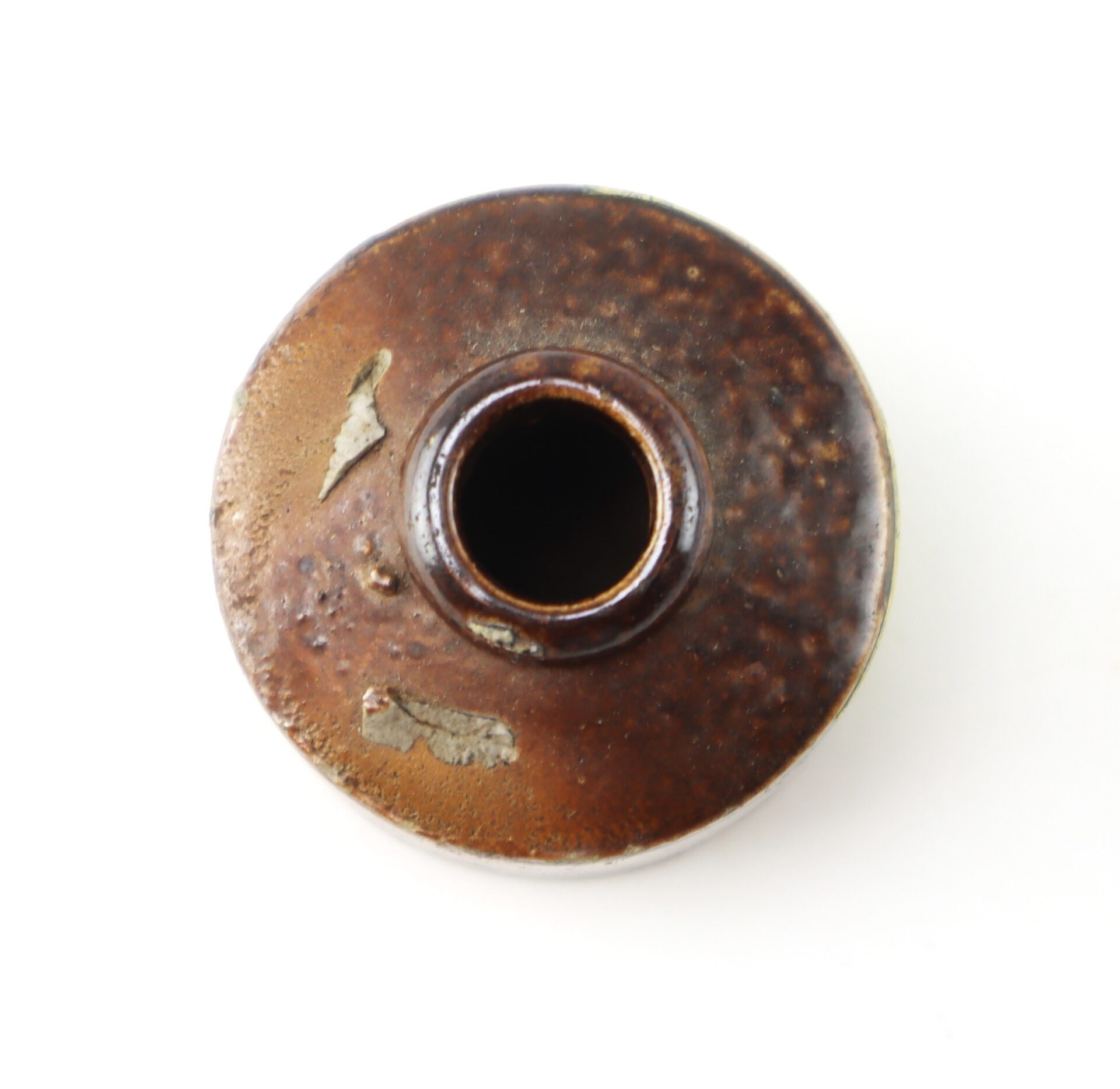Top-down view of a small, round, brown ceramic bottle with a narrow neck.