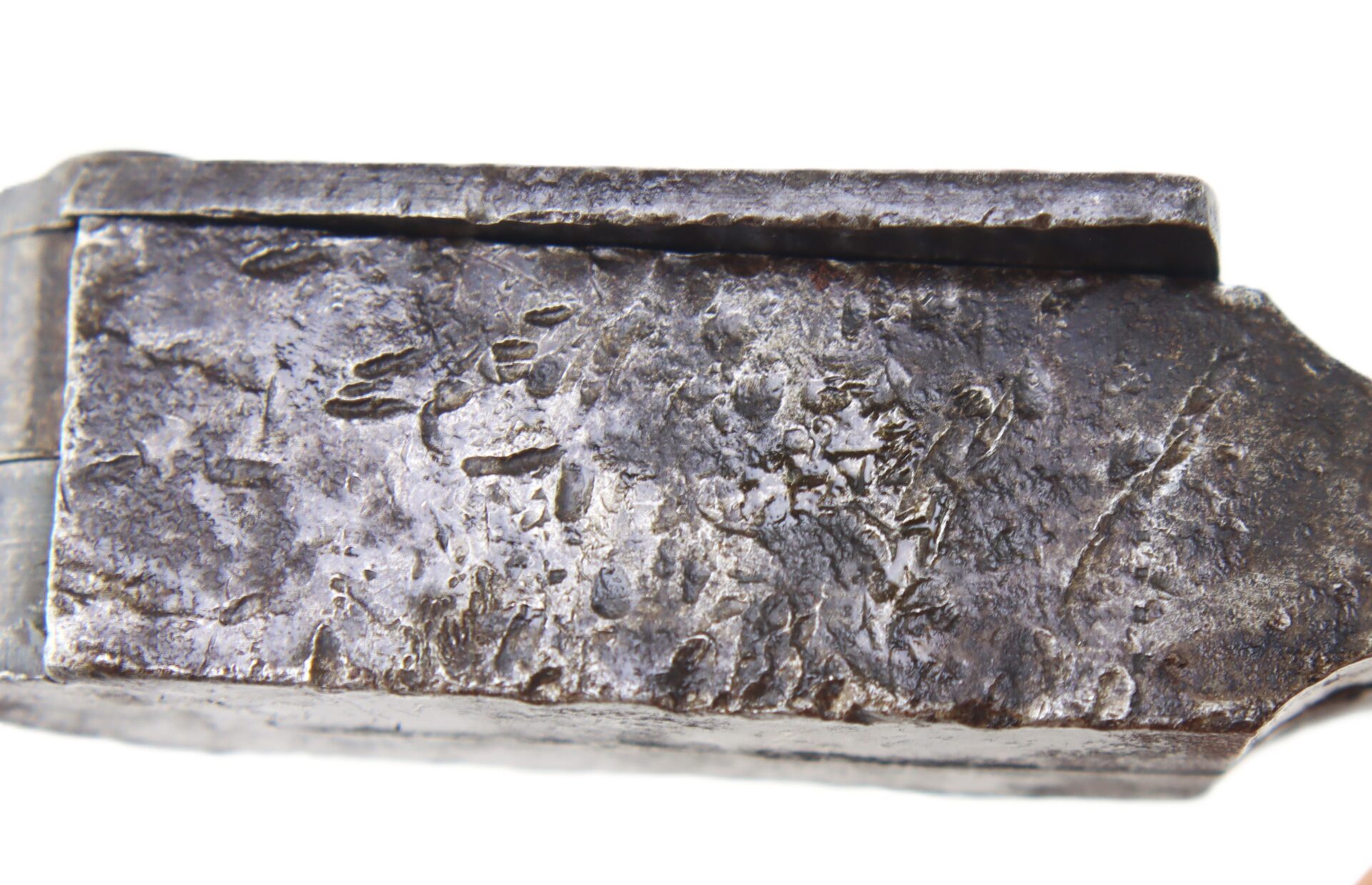 Close-up view of a pitted, weathered metal surface.