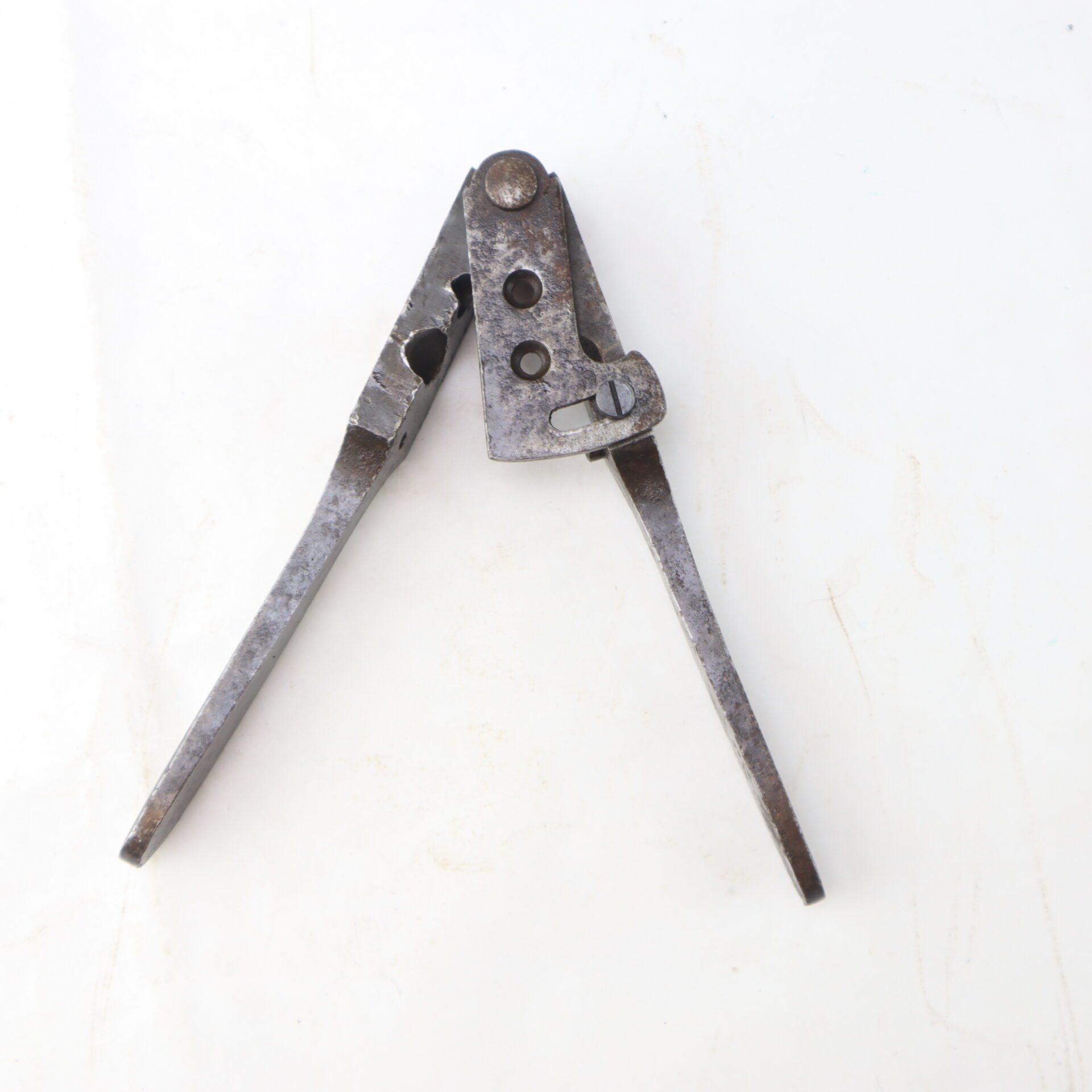 A vintage metal hand tool with two handles and a pivoting head with circular openings.