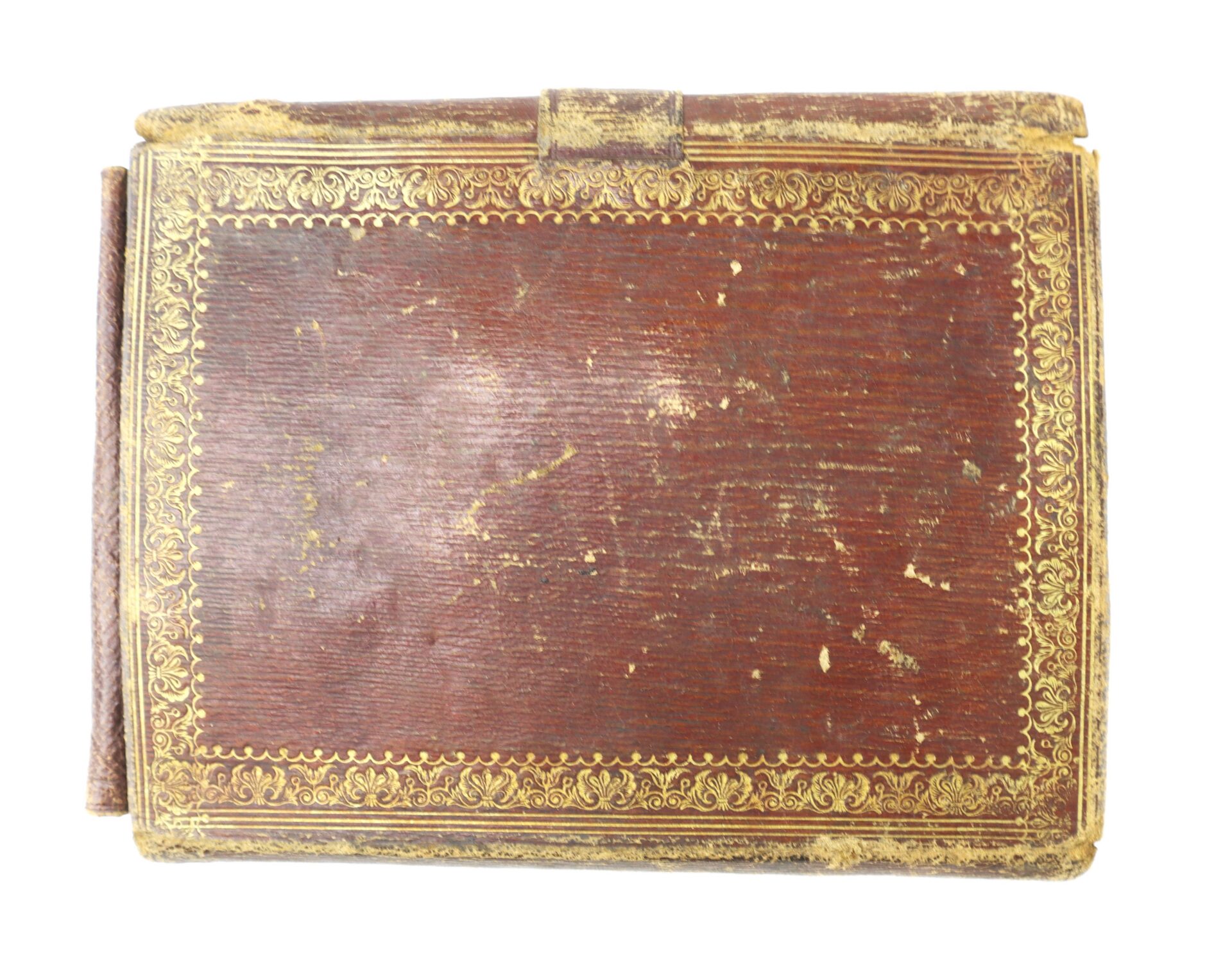 A worn, rectangular brown leather book with decorative gold-tooled borders.