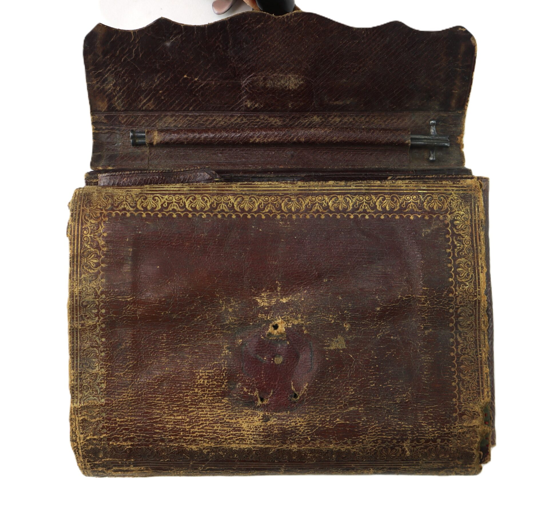An antique, leather-bound book with a gold-tooled border and an open top flap.